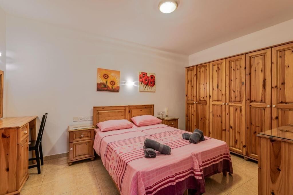 Una camera da letto con un letto in legno, una scrivania e un armadio.