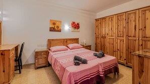 Une chambre à coucher avec un lit en bois, un bureau et une armoire.