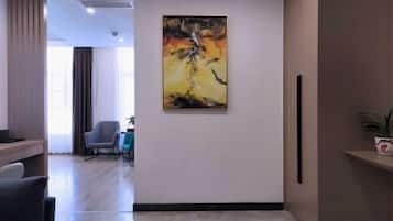 Un vestíbulo de hotel con diseño moderno, que presenta un cuadro abstracto de gran tamaño en la pared, una recepción y una zona de estar con sillones.