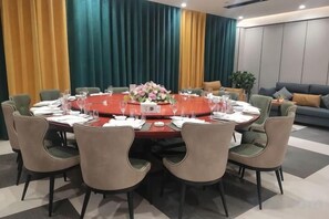 A conference room with a round table, chairs, and a sofa in the background. - Elegance Hotel (Suqian)