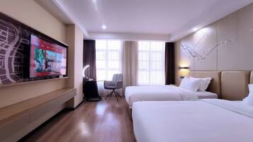A hotel room with two beds, a TV on the wall, a desk, and a chair.