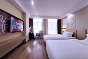 Una habitación de hotel con dos camas, un televisor en la pared, un escritorio y una silla.