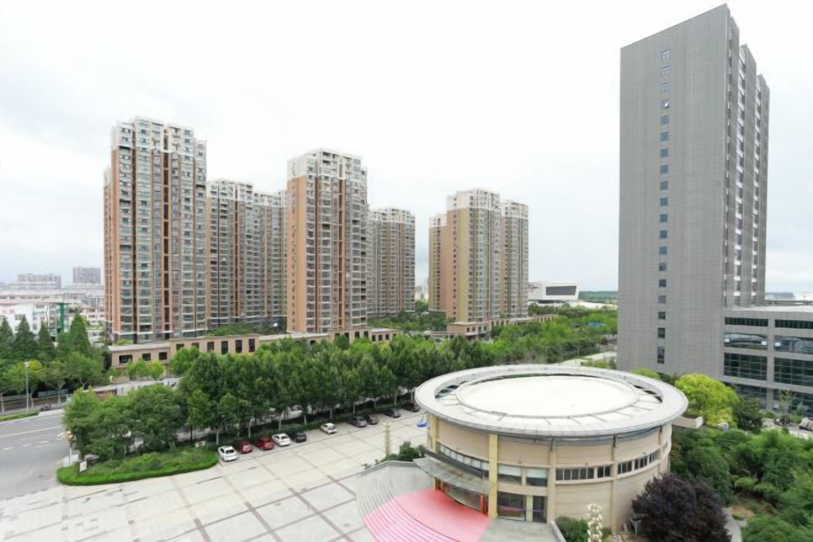 A residential area with high-rise buildings, a circular plaza, and a parking lot.