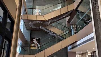 Un interior de varios niveles con barandas de vidrio y una escalera en espiral.