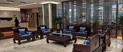 A hotel lobby with seating arrangements, a reception desk, and a decorative partition.
