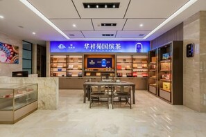 A modern interior with a reception desk, seating area, and shelves displaying products. - Elegance Hotel (Suqian)