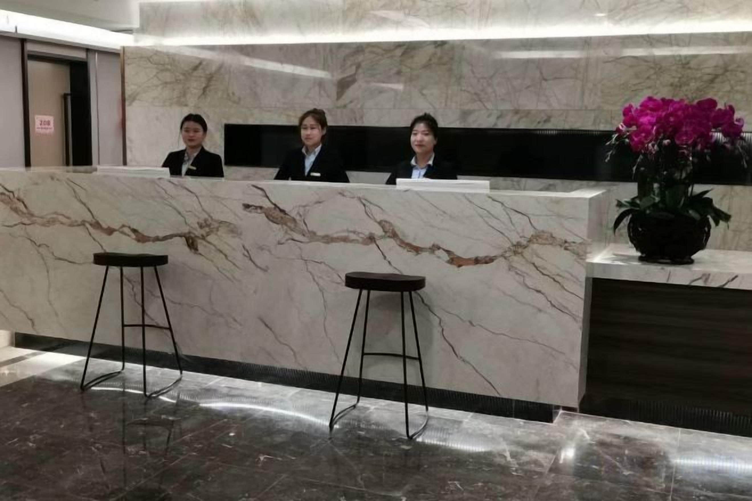Un mostrador de recepción con encimera de mármol y dos taburetes.