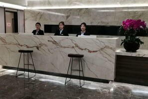 Un mostrador de recepción con encimera de mármol y dos taburetes.