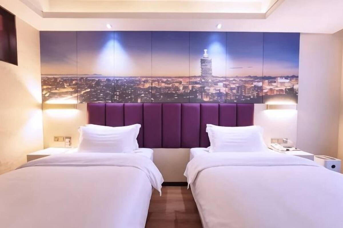 A hotel room with two beds, a cityscape mural on the wall, and a modern headboard.
