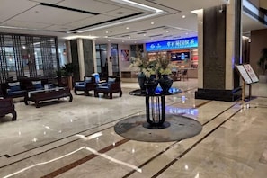 A hotel lobby with seating areas, a reception desk, and a digital display. - Elegance Hotel (Suqian)