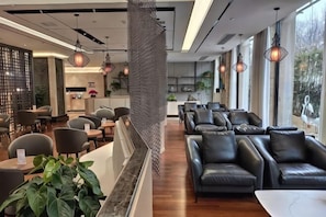 A modern interior with leather seating, a reception area, and large windows. - Elegance Hotel (Suqian)