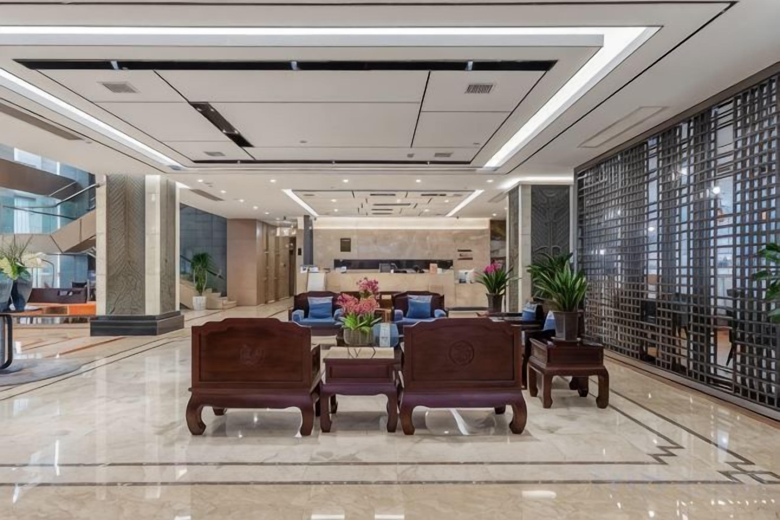 A hotel lobby with a reception desk, seating area, and a view of the outside.