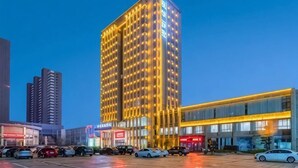 A high-rise hotel with multiple floors, a parking lot in front, and adjacent commercial buildings. - Elegance Hotel (Suqian)