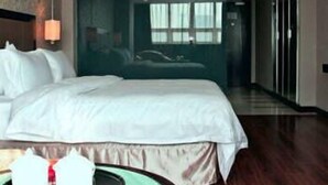 A hotel room with a large bed, a bedside table, and a view of another room through a glass door. - Fujian Enjoy Hotel (Fuzhou)