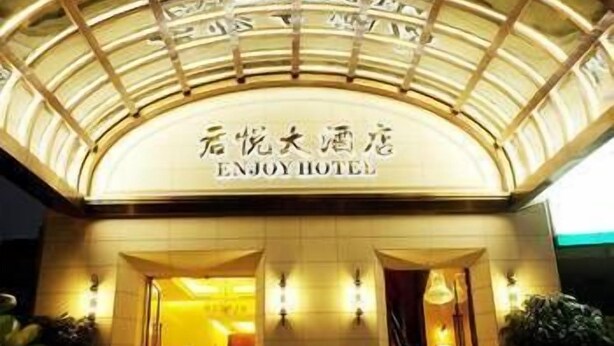 The exterior of the ENJOY HOTEL with a large, illuminated sign and a curved roof structure. - Fujian Enjoy Hotel (Fuzhou)