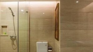 A modern bathroom with a glass-enclosed shower, a toilet, and a framed picture on the wall. - Fujian Enjoy Hotel (Fuzhou)