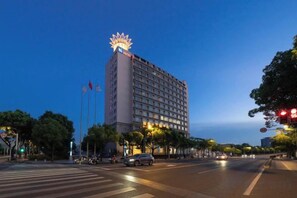 A hotel with a prominent illuminated sign, a large building with multiple floors, and a crosswalk in the foreground. - Sunkist International Hotel (Shanghai)