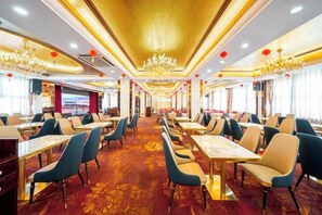 A restaurant with tables and chairs arranged in a spacious layout, featuring a patterned carpet and a chandelier. - Sunkist International Hotel (Shanghai)