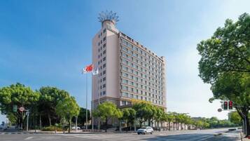 A multi-story hotel with a flat facade, located at a street corner with a crosswalk and traffic lights.