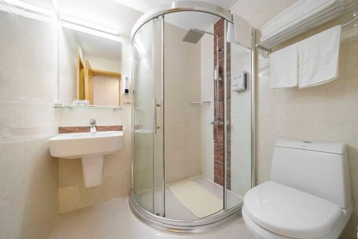 A modern bathroom with a glass-enclosed shower, a white sink, and a toilet.