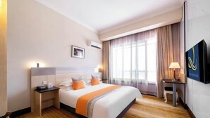 A hotel room with a bed, bedside table, lamp, and a TV on the wall. - Sunkist International Hotel (Shanghai)
