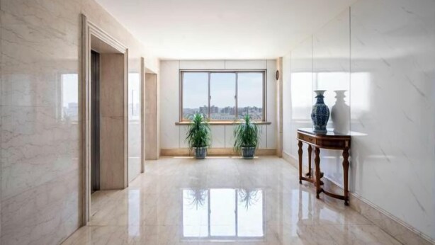 A spacious hallway with a large window, marble flooring, and two potted plants. - Sunkist International Hotel (Shanghai)