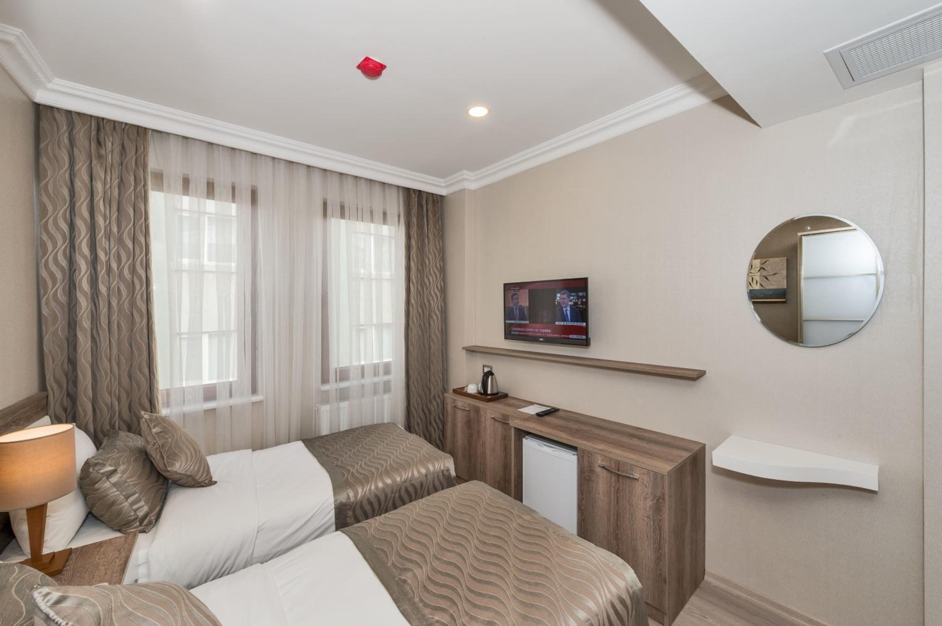 Camera d'albergo con due letti, una TV, uno specchio e una piccola scrivania con una macchina per il caffè.