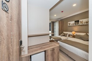 A hotel room with a wooden desk, two beds, a nightstand with a lamp, and a wall-mounted artwork. - Alphonse Hotel (Istanbul)