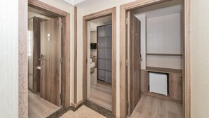 A hallway with wooden doors leading to different rooms, including a bathroom with a glass shower and a storage cabinet. - Alphonse Hotel (Istanbul)