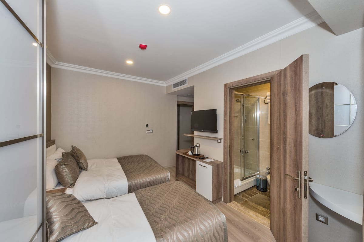 A modern hotel room with a bed, a desk, a shower, and a television.