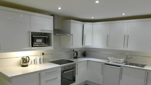 A modern kitchen with white cabinets, a microwave, a stove, and a sink.