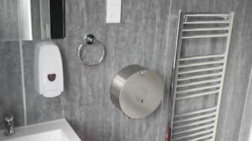 A modern bathroom with a white sink, a mirror, a towel rack, and a hand dryer.