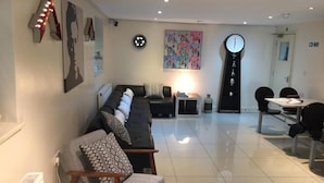 A modern living room with a sofa, a dining table, and a clock on the wall.