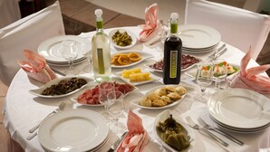 A round dining table set with white plates, multiple glasses, and various dishes including pasta, meats, and vegetables. - Agriturismo Menhir (Villagrande Strisaili)