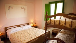 A bedroom with a double bed, a nightstand, a bedside lamp, and a window with green shutters. - Agriturismo Menhir (Villagrande Strisaili)
