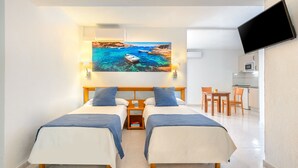 A hotel room with two beds, a painting of a coastal scene, a TV, a desk, and a kitchenette. - Vibra Calima Apartamentos - Adults Only (Sant Antoni de Portmany)