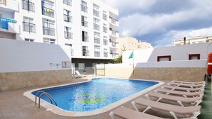 Una piscina con sillas de descanso y un muro de piedra.