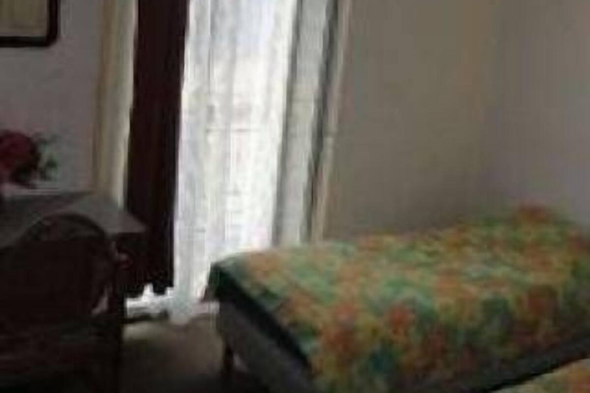 A bedroom with a bed, a desk, and a window with curtains.