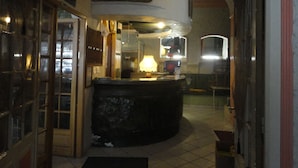 A bar area with a counter, a sign above it, and a window in the background. - Hôtel Saint Christophe (Lourdes)