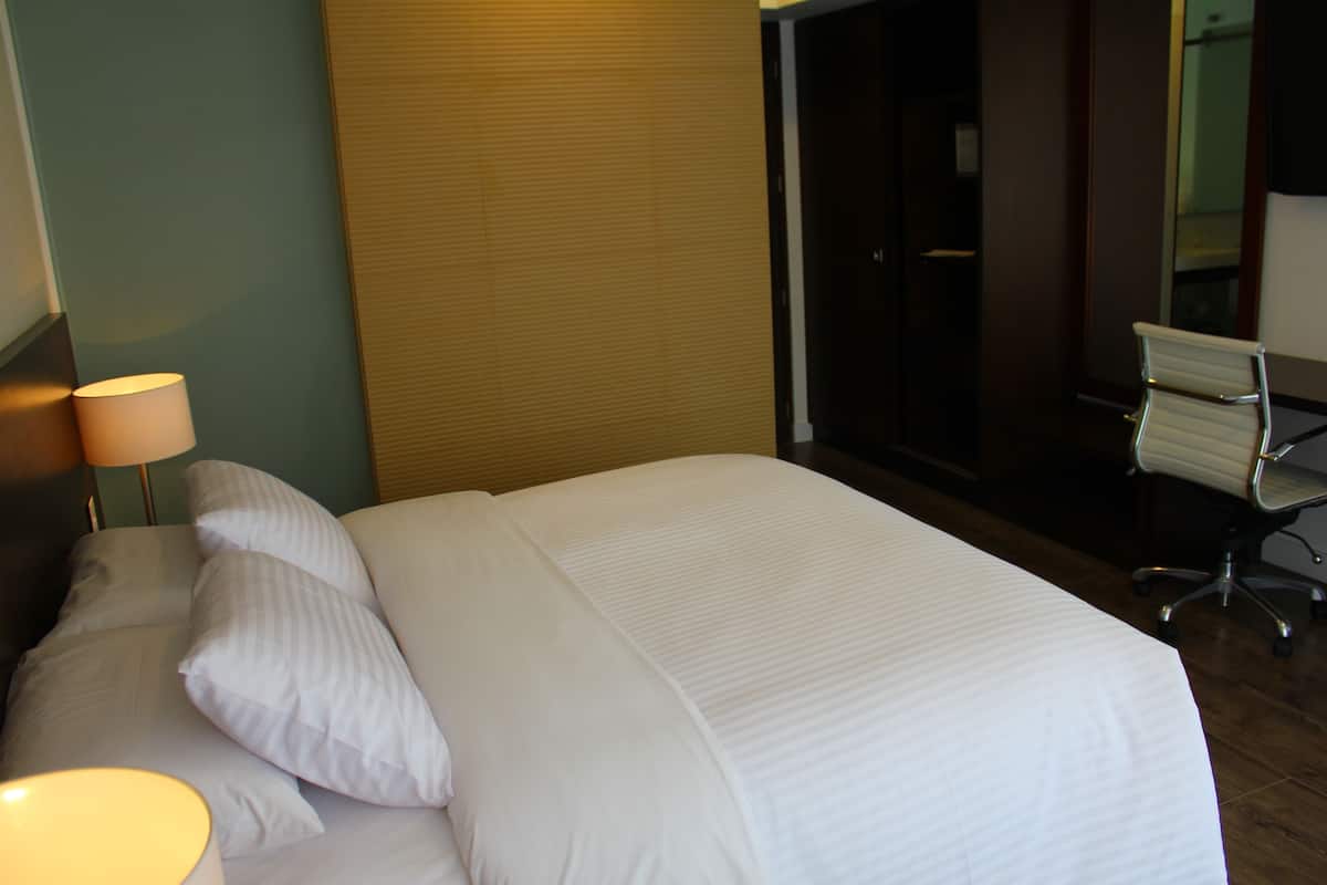 A hotel room with a large bed, a desk, and a chair.