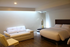 A modern bedroom with a bed, a sofa, and a nightstand.