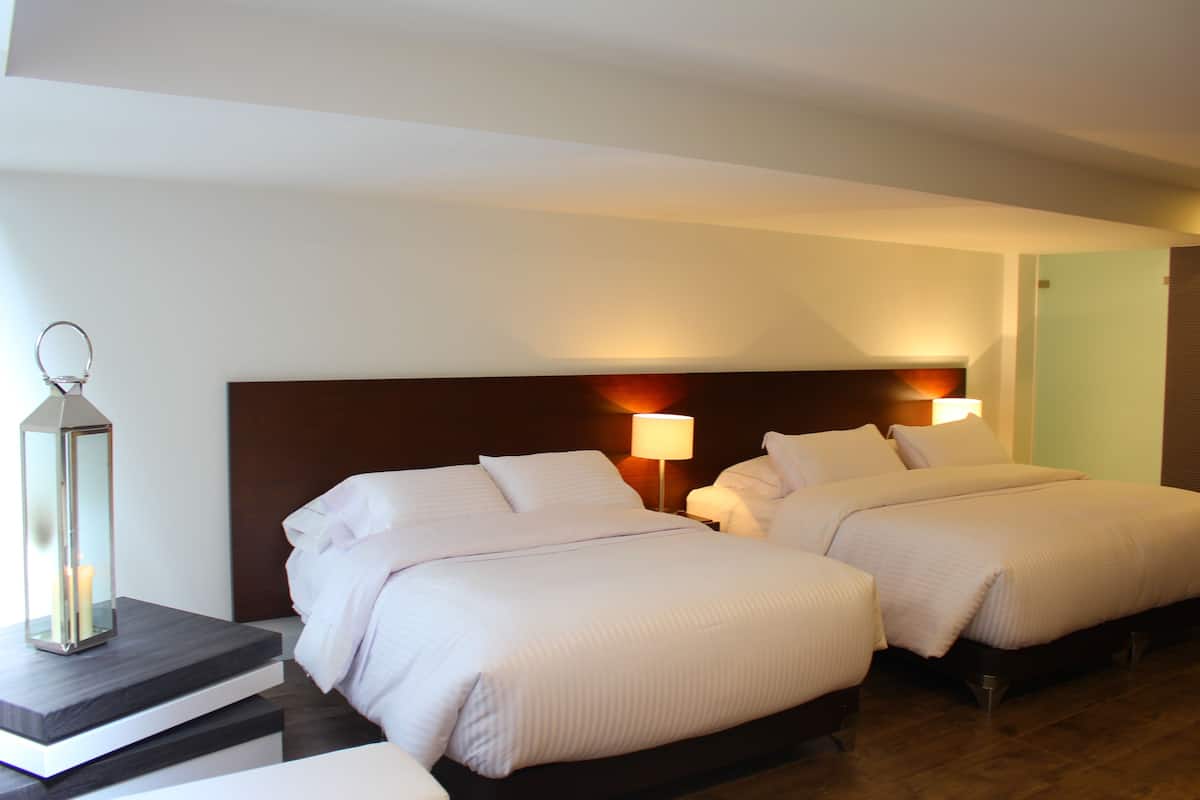 A hotel room with two beds, a nightstand, a lamp, and a decorative lantern.