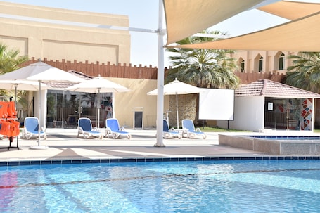 Una piscina al aire libre, sombrillas, sillones reclinables de piscina