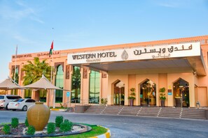 A Western Hotel with a modern facade, large entrance, and palm trees in the foreground.
