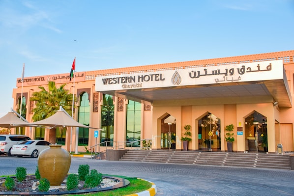 Un hôtel de style occidental, doté d’une façade moderne, d’une grande entrée et de palmiers en premier plan.