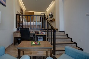Uma sala de estar moderna com uma mesa de centro de madeira, um sofá azul e uma escada que leva a um quarto.