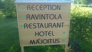 A wooden sign with the words "RECEPTION," "RAVINTOLA RESTAURANT HOTEL MAJOITUS" and directional arrows. - Koivukankare (Kaarina)