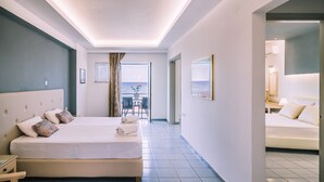 Ein Hotelzimmer mit einem großen Bett, einem Schreibtisch und Meerblick aus dem Fenster.