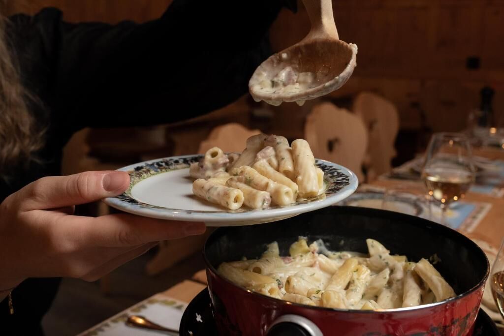 A person serving pasta from a pot.