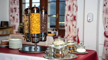 A breakfast buffet with various food items and a coffee dispenser.